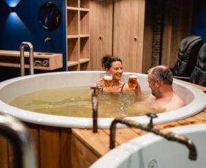 Twee mensen genieten met een biertje in de hand van de bierspa